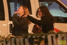 two people standing next to each other near a white van with christmas decorations on it