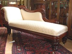 an ornate wooden chaise lounge with beige upholster and white fabric on top