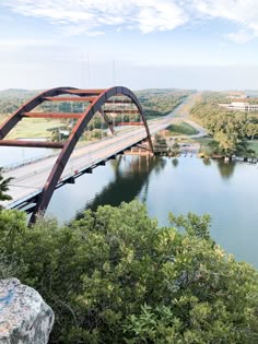 a large bridge over a river next to a lush green forest