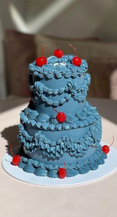 a three tiered blue cake with cherries on it