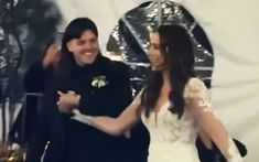 two people standing next to each other in front of a white tent