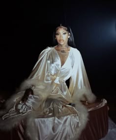 a mannequin sitting on top of a bed in a white dress and fur stole