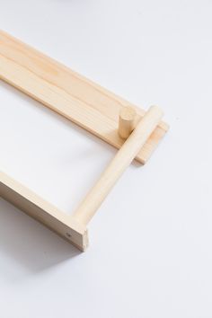 a close up of a wooden frame on a white surface with a small object in the background