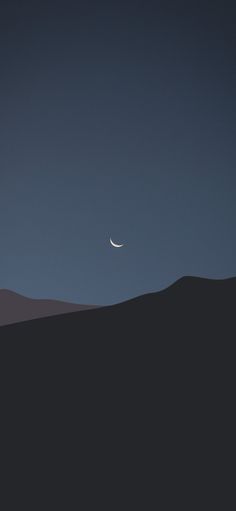 the moon is seen in the sky over a hill