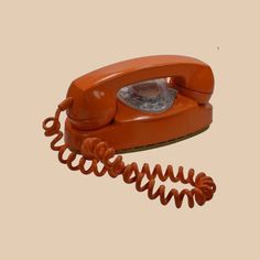 an orange phone is laying on its side with the cord still in it's place