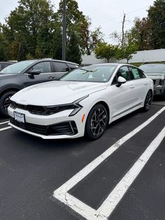 a white car parked in a parking lot next to other cars