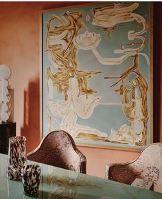 a table with two chairs and a painting on the wall