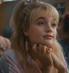 a woman sitting at a table with her hand on her chin and looking off to the side