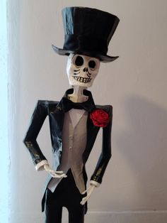 a fake skeleton dressed in a tuxedo and top hat with a red rose