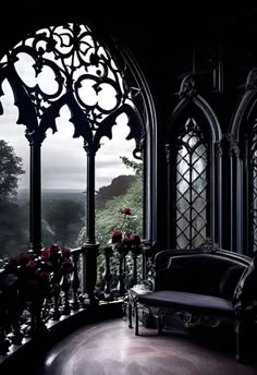 an ornate balcony with black furniture and flowers in the window sill, looking out onto a valley