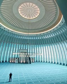 a man standing in the middle of a room with a domed ceiling and glass walls