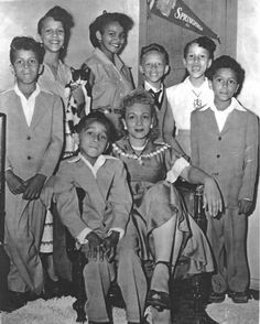 black and white photograph of children in school uniforms posing for the camera with their teacher