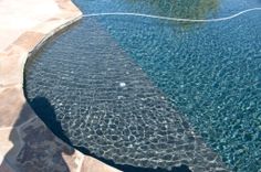 a pool with clear blue water and rocks around it