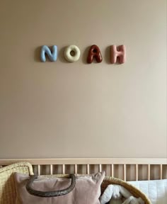 the name noah spelled in small letters above a crib with stuffed animals on it
