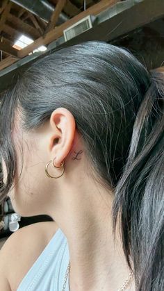 a woman with grey hair wearing a pair of gold hoop earrings and a white tank top