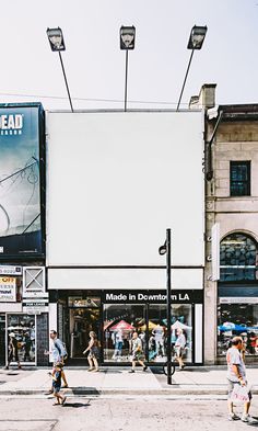 people crossing the street in front of a building with large billboard on it's side