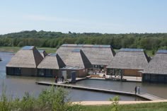 a group of houses sitting on top of a lake next to a dock with grass roofs