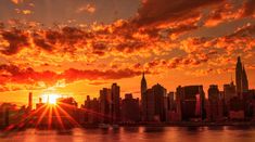 the sun is setting over a city with skyscrapers in the foreground and water below