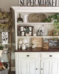 a white hutch filled with lots of items and decor on top of wooden shelves