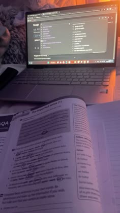 an open laptop computer sitting on top of a book next to a mouse and keyboard