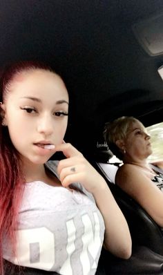 a woman sitting in the back seat of a car talking on a cell phone with another person behind her