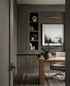 an office with gray walls and wooden floors is pictured in this image, the desk has a plant on it