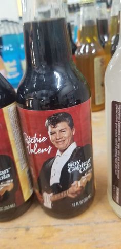 three bottles of alcohol sitting on top of a wooden table next to another bottle with an advertisement on it