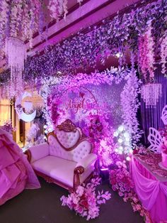an elaborately decorated stage set up with pink and purple flowers on the walls, chandeliers and couches