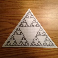 a triangle made out of paper sitting on top of a wooden table