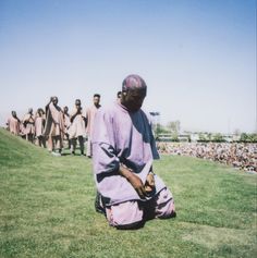 a man sitting on top of a lush green field next to a group of people
