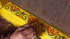 a person is writing on a piece of paper next to a yellow pole with colorful designs