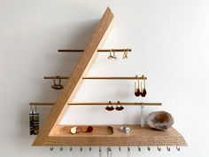 a wooden shelf with several pairs of earrings hanging from it's sides and hooks on the wall
