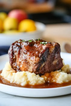 a piece of meat and mashed potatoes on a white plate with gravy