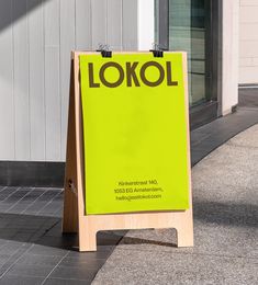 a yellow sign sitting on the side of a road next to a building and sidewalk