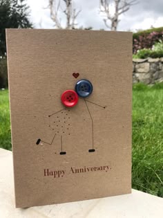 a brown card with two buttons on it and the words happy anniversary written in red