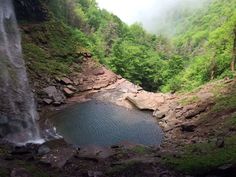a waterfall with a pool in it surrounded by trees