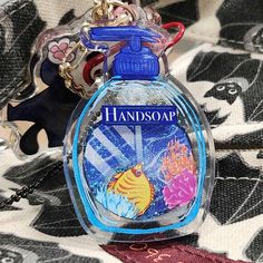 a bottle of hand soap sitting on top of a bed next to a keychain