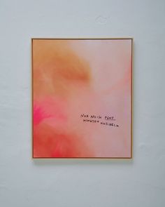 a pink and orange painting hanging on the wall next to a white wall with writing on it