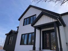 a white house with black trim on the front and side of it's windows
