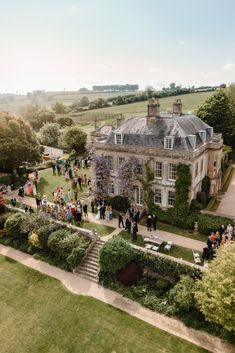 an aerial view of a large house with many people walking around the front yard and lawn