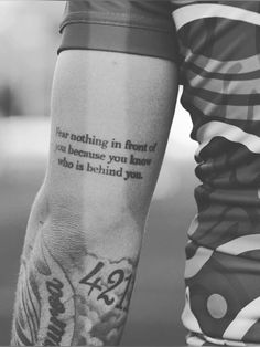 a person with a tattoo on their arm that reads, fear nothing in front of you because you know who is behind you