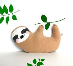 a stuffed slotty hanging from a branch with leaves on it's back and eyes closed