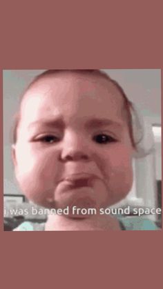 a baby with headphones on is looking at the camera and has an angry look