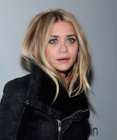 a woman with blonde hair wearing a black jacket