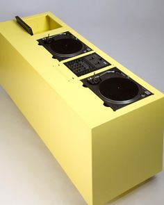 two turntables sitting on top of a yellow box with black speakers in it