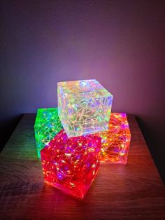 three glowing cubes sitting on top of a wooden table