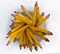 a group of yellow pencils sitting in a metal cup