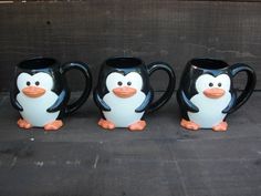 three black and white penguin mugs sitting next to each other