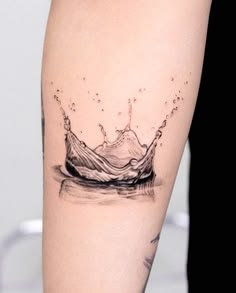 a black and white photo of a water splash tattoo on the right calf's leg