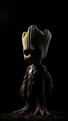 the baby groote is sitting in the dark with its head turned to look like it